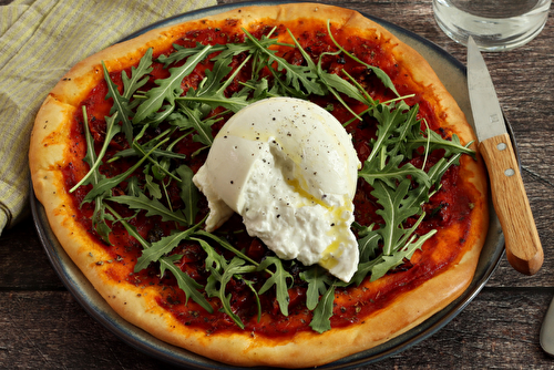 Pizza à la sauce tomate et burrata fraîche, tomates cerises confites, roquette et une pointe de pesto