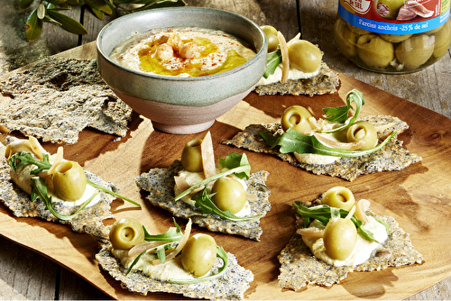 Crackers aux graines au houmous et olives aux anchois, roquette