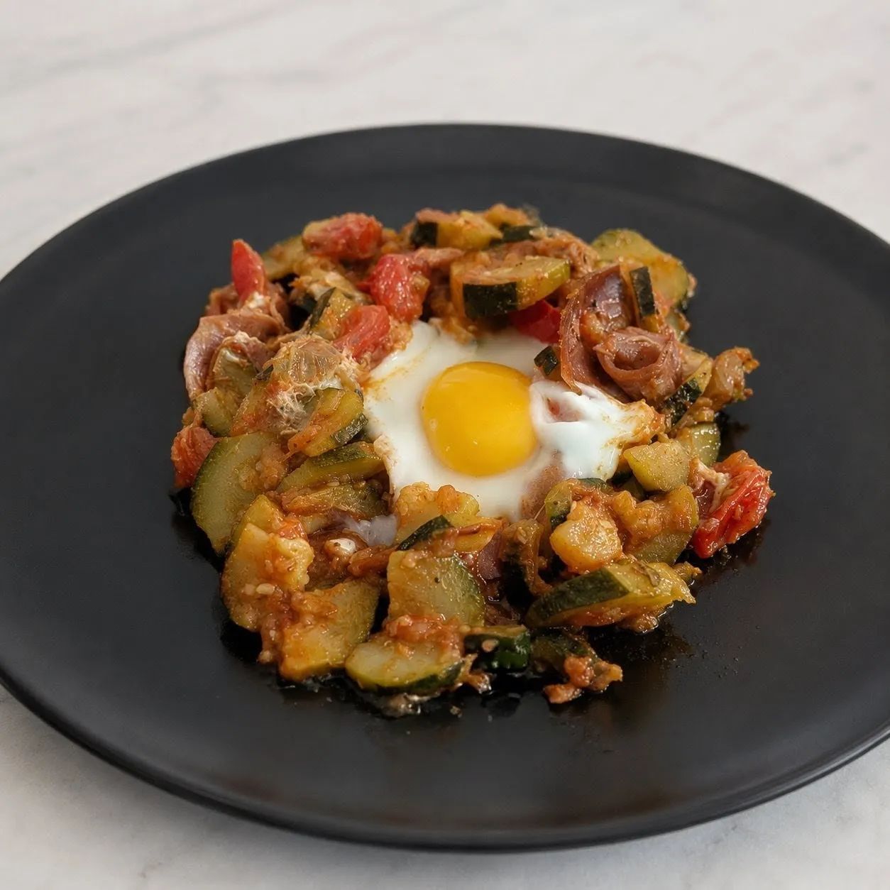 Poêlée de courgettes avec tomates, jambon de pays et œufs pochés
