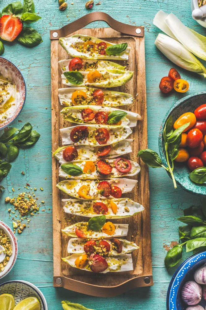 Feuilles d’endives apéritives à la ricotta, tomates cerise basilic et pistaches concassées