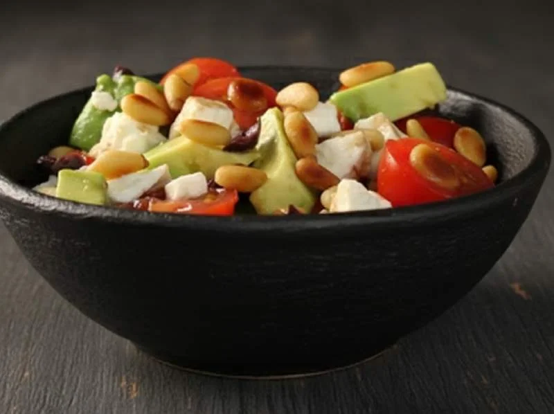 Salade d'avocats avec feta, pignons, tomates et olives noires