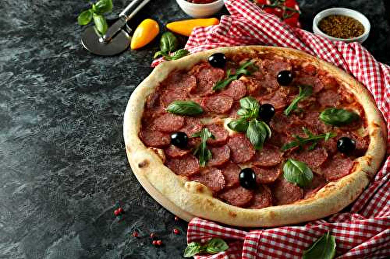 Pizza traditionnelle au salami sur lit de sauce tomate, mozzarella fondante et huile d'olive parfumée